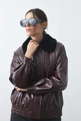 Campera de cuero sintético con acabado satinado, silueta relajada y elástico en la cintura. Presenta cuello con textura de piel sintética, cierre frontal y bolsillos laterales.