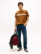 Remera de manga corta Tommy Hilfiger color marrón, con cuello redondo y una franja horizontal blanca en el pecho que incluye el logo de la marca estampado.