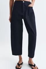 Pantalón de jean azul oscuro de tiro medio, con corte holgado y diseño de pierna ancha. Presenta cintura elástica en la parte posterior, cierre frontal con cremallera y botón metálico, y bolsillos de plastrón en el delantero.