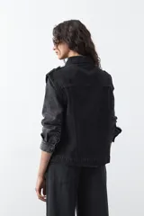 Chaleco de jean en tono celeste claro, con corte recto, cuello camisero, cierre frontal con botones metálicos y costuras visibles.