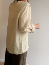 Camisa de lino color marrón, de silueta relajada y corte oversize, con cuello mao, mangas largas remangadas y cierre frontal con botones.