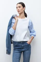 Remera de algodón con cuerpo liso en color blanco y mangas abullonadas de tela camisera con estampado de rayas finas en azul y blanco.