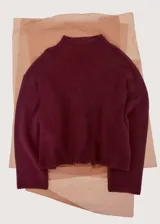 Sweater de punto color bordó, con cuello alto, manga larga y diseño holgado.