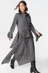 Falda midi de corte asimétrico con diseño de rayas horizontales en blanco y negro. Confeccionada en tejido satinado con caída fluida.