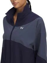 Campera deportiva de corte ligero con diseño de bloques de color en tonos azul marino y gris. Presenta cierre frontal completo, cuello alto, bolsillos laterales y puños con elástico. Incluye el logo de la marca en el pecho.