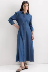 Vestido camisero largo de denim azul, con cuello clásico, mangas 3/4 abullonadas y falda amplia con bolsillos laterales.