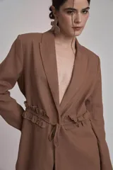 Blazer negro con solapas de muesca, corte holgado, cierre frontal con lazo y detalle de volados en los bolsillos.