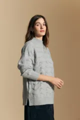 Sweater de punto color beige con diseño geométrico en relieve, cuello alto y mangas largas con puños acanalados.