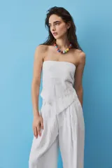 Blusa strapless azul marino de corte asimétrico con terminación en punta y flecos sutiles en el borde inferior, diseño de escote palabra de honor.