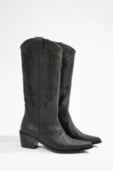 Botas texanas de cuero negro con bordados decorativos en el lateral de la caña, punta fina y taco bajo.