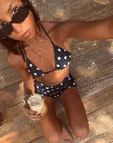 Conjunto de bikini con estampado de lunares blancos sobre fondo negro. El top es de estilo triangular con tiras para atar y la parte inferior es una bombacha tipo vedetina con laterales ajustables.