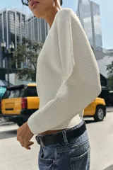 Jersey de punto rib color blanco, con cuello barco y mangas largas con sisas anchas.