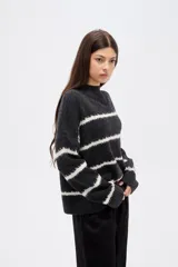 Sweater de punto con diseño de rayas horizontales en contraste, cuello alto y corte holgado con mangas largas.