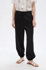Pantalón de poliéster color negro, de tiro alto y corte holgado con frunces en los tobillos.