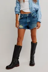Short de denim de tiro medio y calce relajado, con cierre de cremallera y botón, cinco bolsillos, y detalles de desgastes y deshilachados.
