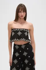 Top cropped negro, estilo strapless, con elástico en el busto y ruedo, y bordados blancos con motivos florales y geométricos.