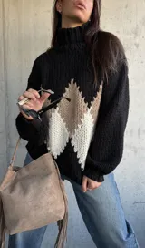 Polerón de tejido grueso con cuello alto, diseño de rombos en tonos negro, beige y blanco, y mangas largas con puños ajustados.