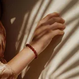 Pulsera elástica con cuentas redondas de ágata roja y cierre de acero hipoalergénico con baño de oro.