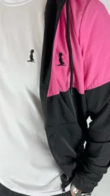 Campera deportiva con capucha, combinada en fucsia y negro, con cierre frontal y bolsillos laterales.