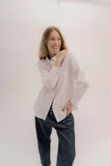 Camisa de manga larga color rosa claro con textura, cuello y puños blancos contrastantes. Los puños tienen tres botones rosados.