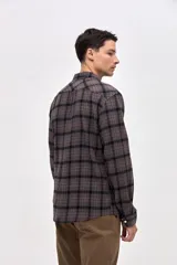 Camisa de corte regular fit, confeccionada en tela de algodón con diseño de cuadros en tonos marrones y negros. Presenta cuello clásico, cierre frontal con botones personalizados y un bolsillo en el pecho con el logo de la marca bordado.