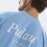 Remera negra de corte boxy con costuras a la vista en contraste de color blanco. Presenta un pequeño logo estampado en el centro del pecho y una frase bordada en el bajo lateral. Posee mangas cortas y cuello redondo.