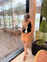Musculosa de tejido de punto gris, con tirantes finos, escote en V y un llamativo aplique frontal de cuero plateado en forma de flecha.
