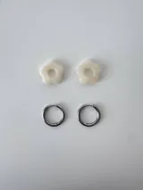Aros de acero quirúrgico argolla con dije colgante en forma de flor de resina color gris marmoleado.