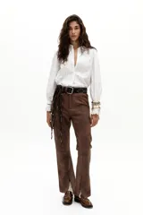 Camisa blanca de popelina de algodón con alforzas en el frente, cuello con terminación ondulada y bordados, y puños con vainillas. Tiene un corte levemente entallado, ruedo curvo y un sutil frunce en los hombros.