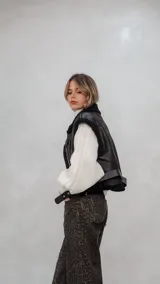 Chaleco de eco cuero negro con interior de corderito sintético, diseño oversize, cierre frontal y cinturón ajustable en el ruedo.