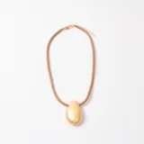 Collar con cordón de cuero marrón y dije central en forma de gota con acabado dorado texturizado.