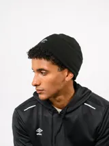 Gorro tipo beanie de Umbro, confeccionado en tejido polar negro, con el logo de la marca bordado en blanco en la parte frontal.