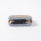 Monedero de cuero sintético con textura trenzada, color celeste, con cierre perimetral y tarjetero exterior.