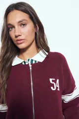 Campera de punto tipo cardigan en color bordó, con cierre frontal, cuello redondo y diseño estilo universitario. Presenta el número 54 bordado en blanco en el pecho y franjas blancas en las mangas.