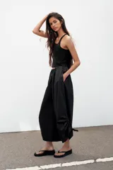 Pantalón culotte de tiro medio, color verde militar, con cintura elástica y bolsillos laterales ocultos. Presenta un diseño de bajo ancho con aberturas ajustables mediante cordones fruncidos en los laterales.