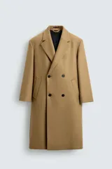 Abrigo largo color camel, de corte relajado (relaxed fit), confeccionado en tejido con mezcla de lana. Presenta cuello con solapas de muesca, manga larga, bolsillos de vivo en cadera, bolsillo interior y cierre frontal de botonadura cruzada.