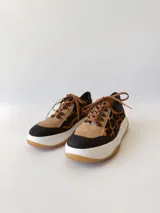 Championes deportivos de cuero con estampado animal print, cordones marrones y suela blanca con base color caramelo.