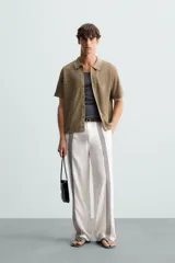 Camisa de punto color marrón, de corte relaxed fit, con cuello solapa, manga corta y acabados en rib. Cierre frontal de botonadura.