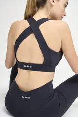 Top deportivo negro con escote redondeado, espalda cruzada y cintura con doble tela.