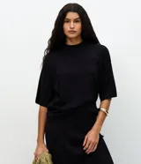 Blusa de manga corta amplia y sisas desplazadas, confeccionada en punto leve de viscosa y poliamida, con cuello redondo ligeramente alto.