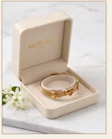 Pulsera de acero con baño de oro, compuesta por una malla metálica flexible y tres dijes pasantes: un corazón con la palabra 'Mamá' grabada, una figura de niña y una figura de niño.