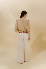 Pantalón de jean gris oscuro, estilo sastrero de tiro medio bajo y corte ancho (wide leg). Presenta costuras marcadas en el frente y un cinturón trenzado marrón con hebilla metálica.