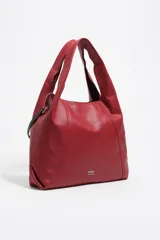 Bolso de mano grande Bimba y Lola modelo Paper, confeccionado en piel vacuna de color rojo. Presenta estructura blanda, asas de hombro fijas, tira lateral con mosquetón y detalle de logo metálico en la parte inferior.