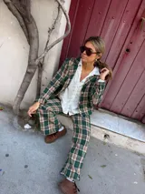 Blazer de corte recto con estampado de cuadros en tonos verdes, beige y negro, con cierre frontal de botones y bolsillos laterales.