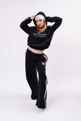 Pantalón deportivo tipo jogger de corte relajado, color negro con franjas laterales blancas y cintura elástica fruncida.