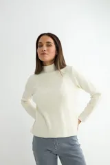 Polera de tejido de punto acanalado en color crema, con cuello alto y mangas largas.