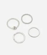 Kit de cuatro anillos finos plateados, confeccionados en metal reciclado. Incluye un anillo liso con nudo, uno con textura trenzada, uno liso con forma orgánica irregular y uno liso con acabado arenado/texturizado.