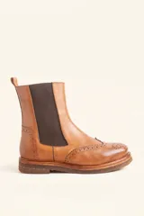Bota tipo Chelsea de cuero vacuno color suela, con diseño brogue en la puntera y laterales. Presenta paneles elásticos laterales en color marrón oscuro, tirador trasero y suela de goma con plataforma.