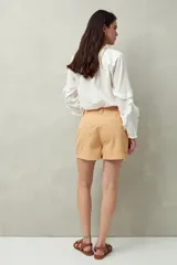 Short de algodón de tiro alto, color beige, con bolsillos delanteros tipo parche con solapa y botones a la vista.