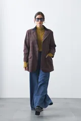 Blazer de corte relajado con estampado de cuadros tipo pied de poule en tonos rojizos y verdes. Presenta solapas clásicas en color azul oscuro y estructura definida.